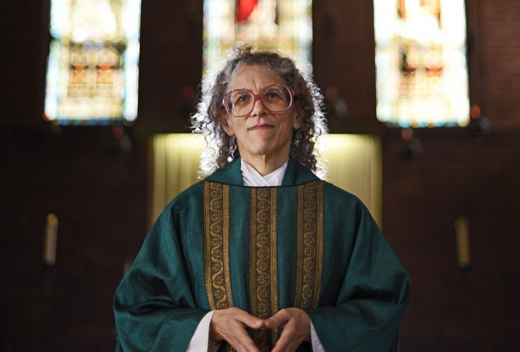 The Reverend Maggie Helwig, photographed on the chancel steps, wears her full "eucharistic vestments" (alb, stole and chasuble) on July 8 2015. Helwig was appointed as priest-in-charge of St.Stephen-In-The-Fields Church in May 2013, and as rector in January 2015 by the Anglican Diocese of Canada. The church is located in downtown Toronto, between the Annex to the north and Kensington Market to the south. Helwig is also a writer and human rights advocate and her writing is on the back burner for the time being since her ministry takes up most of her time.